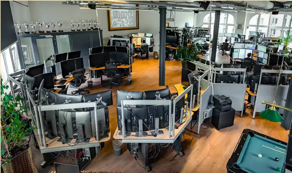A wide view of the trader floor showing multiple trading screens and professionals at work.